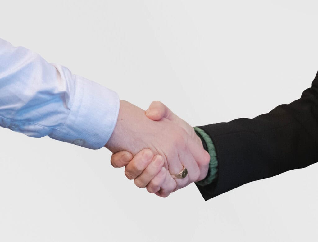 Close-up photo of two business people shaking hands in a professional setting.