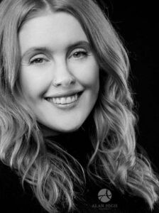 A black and white headshot photo of a beautiful business woman smiling.